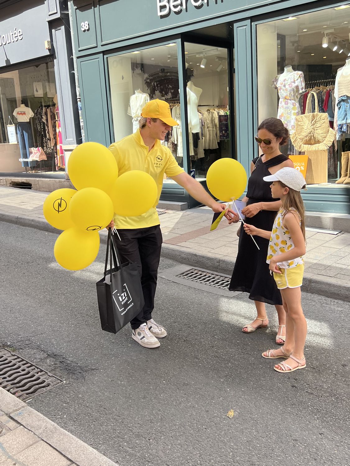 Hôte distribuant des ballons jaunes devant une boutique